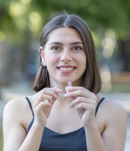 Young woman holding a clear Invisalign aligner